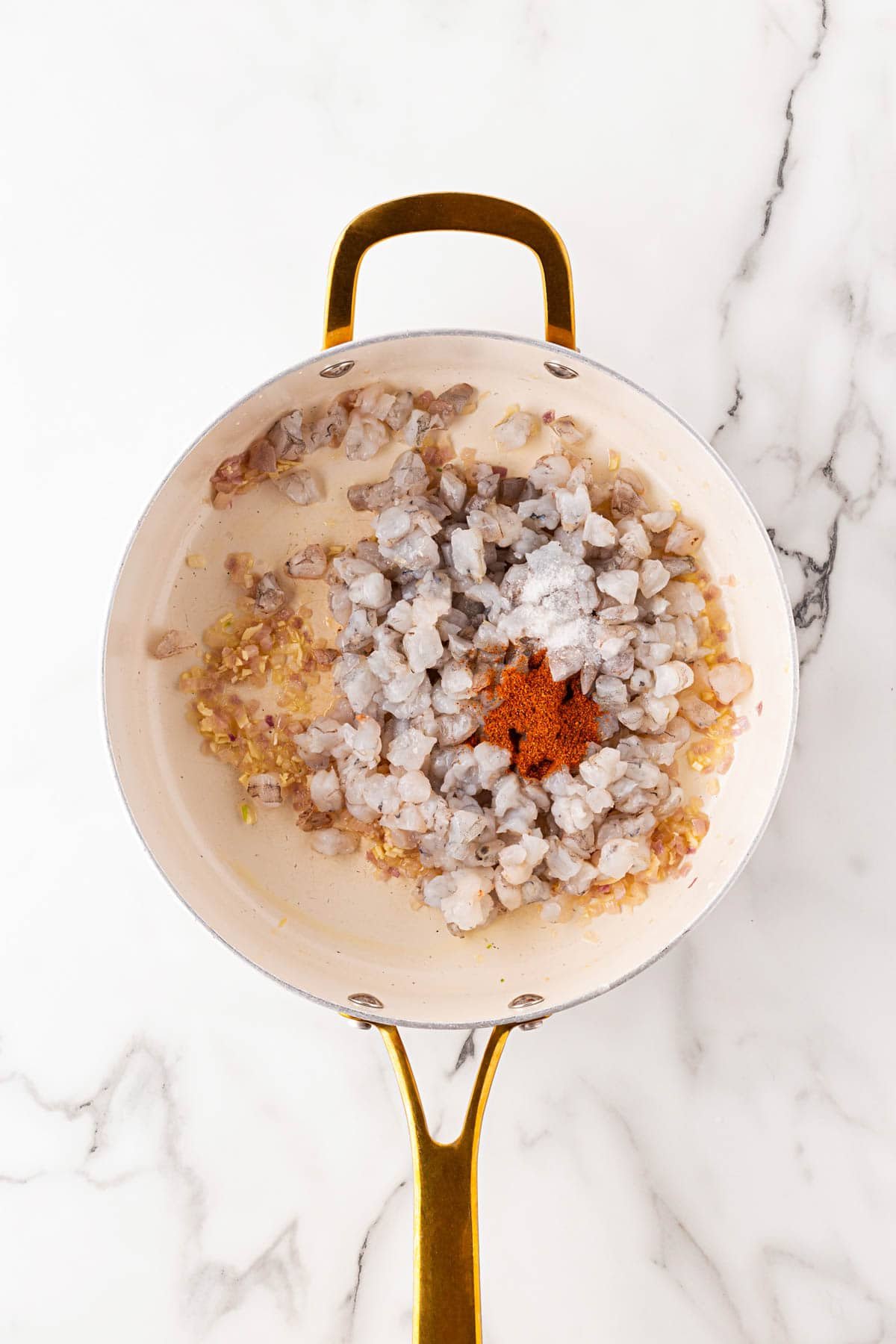 Diced shrimp added to the skillet with sautéed onions and garlic, seasoned with paprika and salt