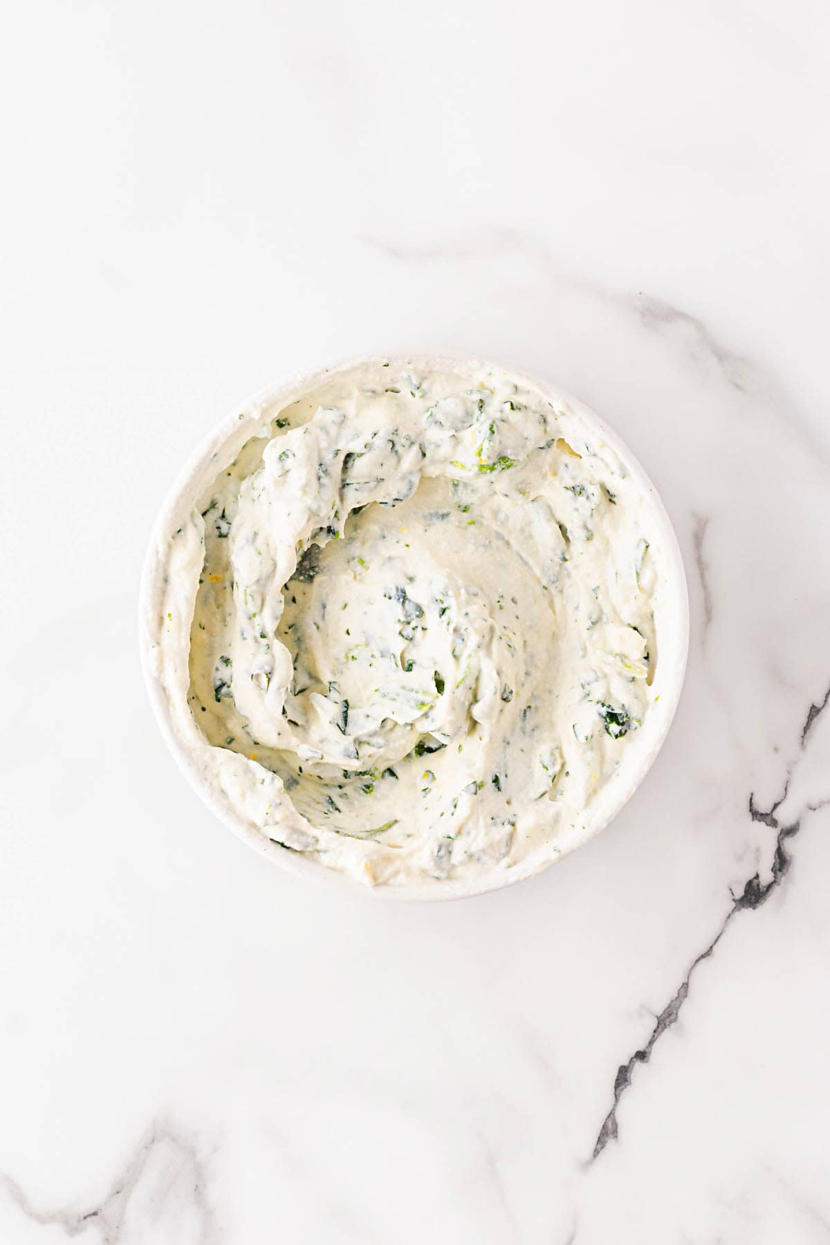 Creamy spinach and ricotta mixture in a white bowl, ready to be used for layering