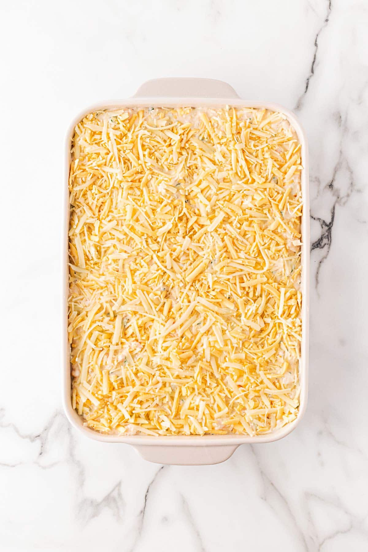 Closeup of the assembled seafood lasagna topped with a thick cheese layer, ready to go into the oven