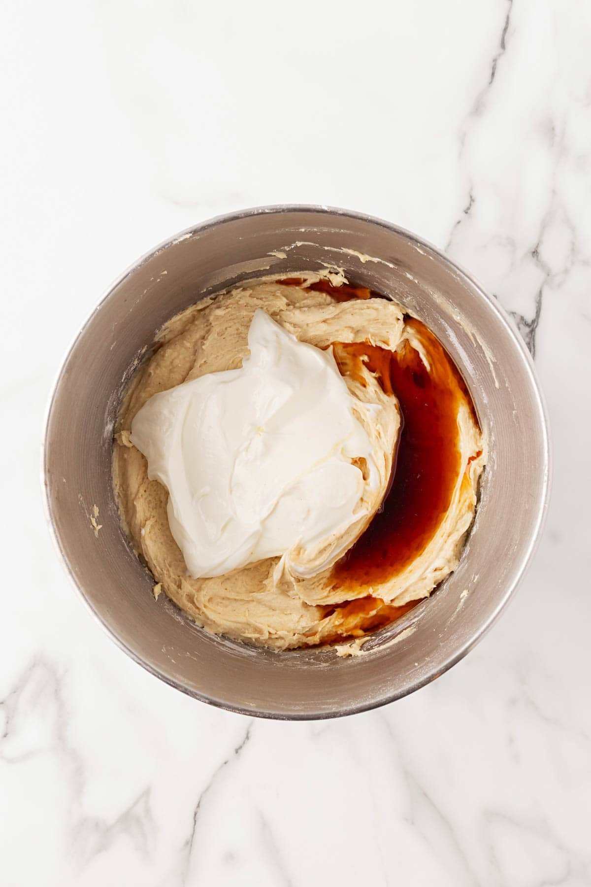 Mixing bowl filled with batter, sour cream, and vanilla extract before combining