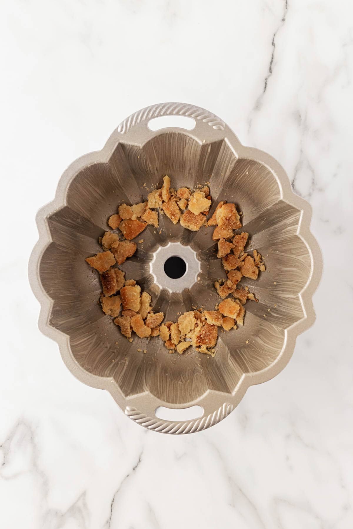 Bundt pan with cinnamon sugar dough crumbles scattered on the bottom for layering