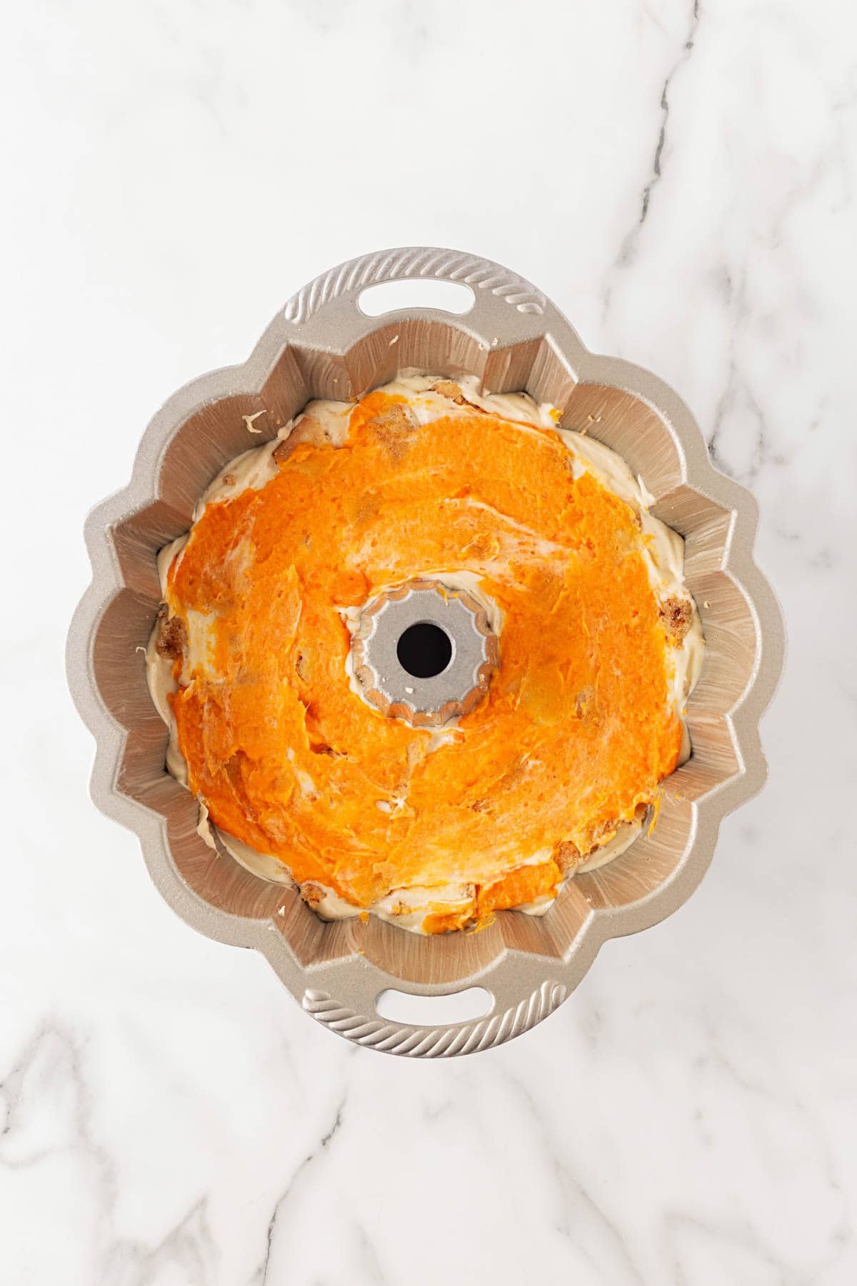 Bundt pan showing a layer of smooth sweet potato filling spread over the batter