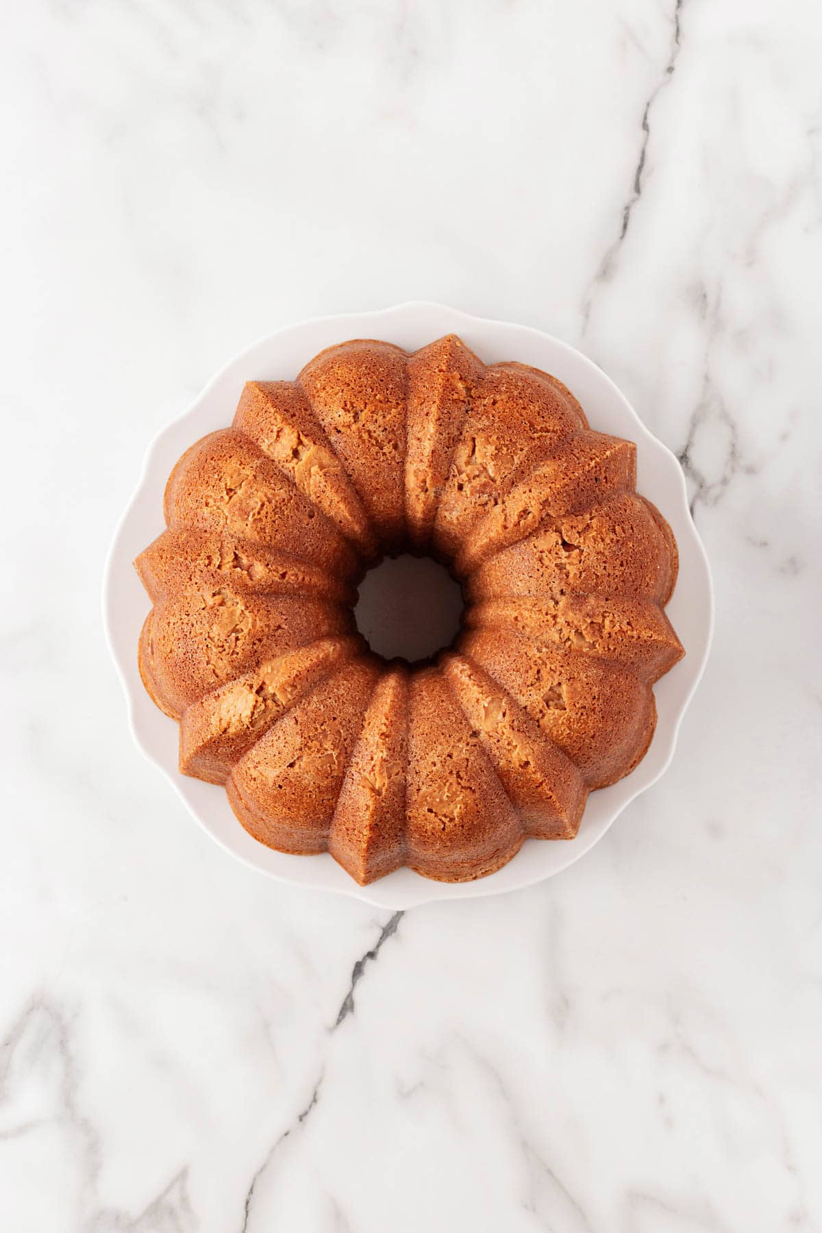 Fully baked pound cake removed from the pan, resting on a white cake plate