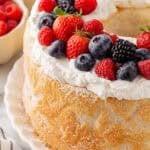 Closeup of a frosted angel food cake topped with fresh strawberries, raspberries, blueberries, and blackberries