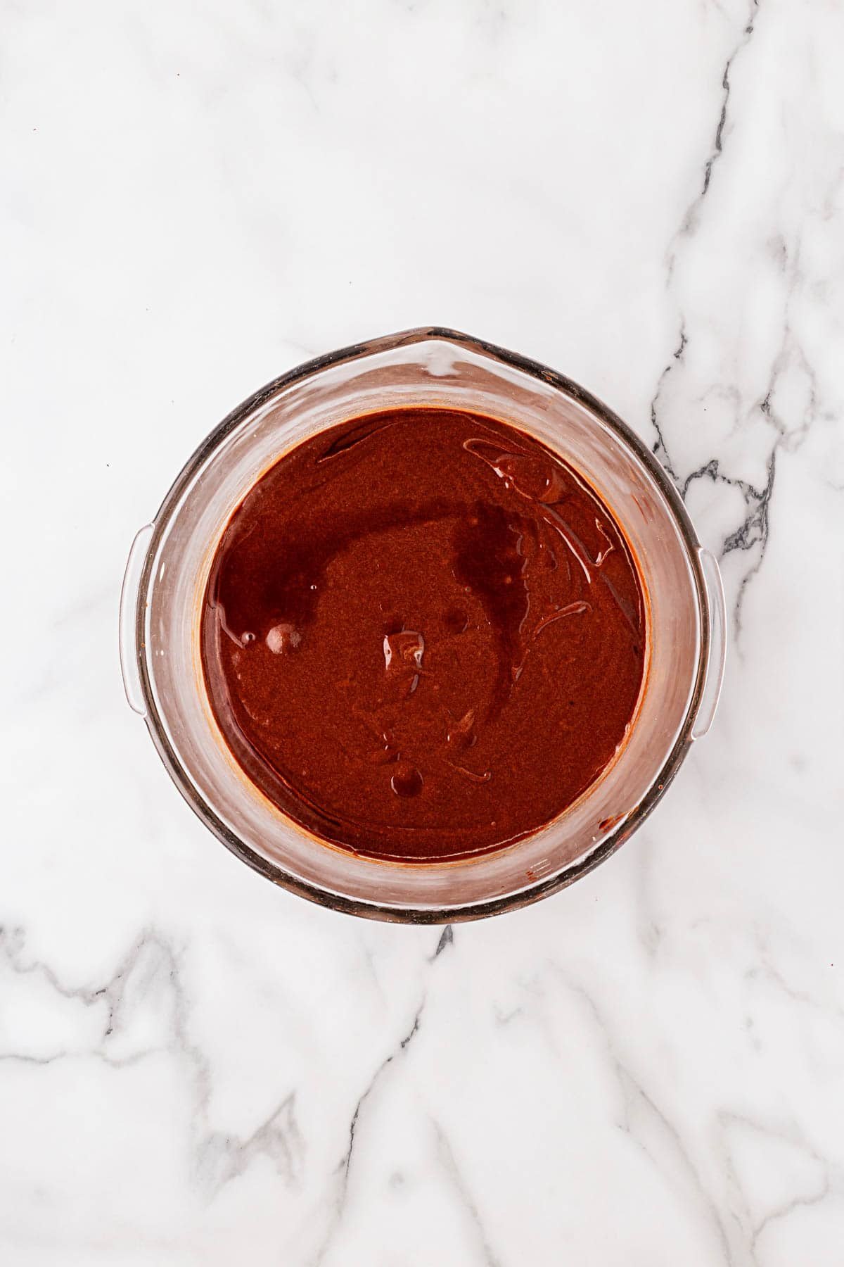 Melted chocolate mixture in a glass bowl, smooth and glossy