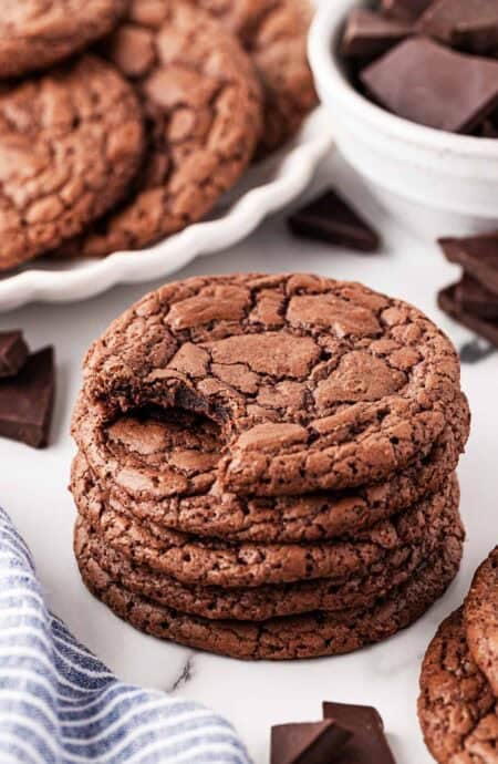 Stack of brownie cookies with a bite taken out of the top cookie, showing their chewy texture