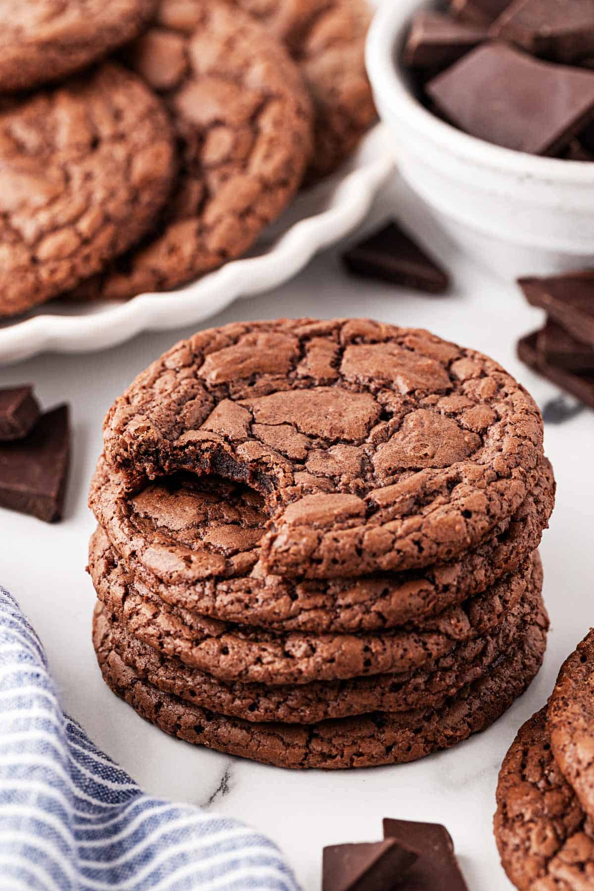 Stack of brownie cookies with a bite taken out of the top cookie, showing their chewy texture