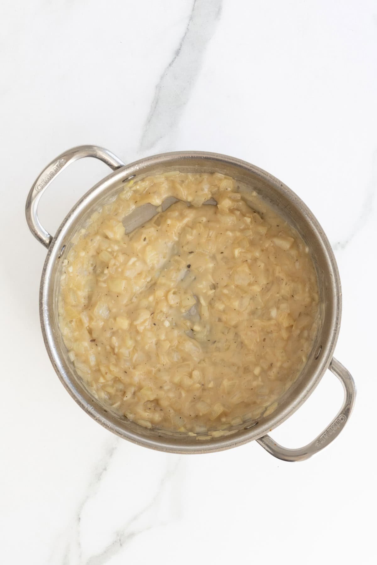Creamy onion mixture thickened in a skillet, forming the base for the alfredo sauce
