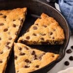 Closeup of sliced chocolate chip skillet cookie inside the pan, showing gooey melted chocolate chips