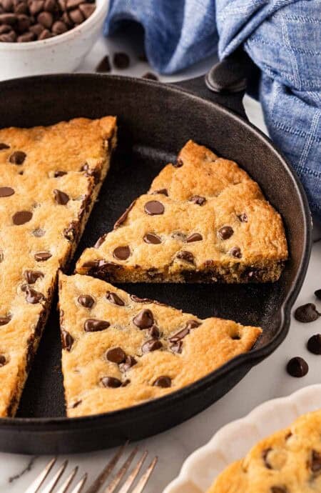 Closeup of sliced chocolate chip skillet cookie inside the pan, showing gooey melted chocolate chips