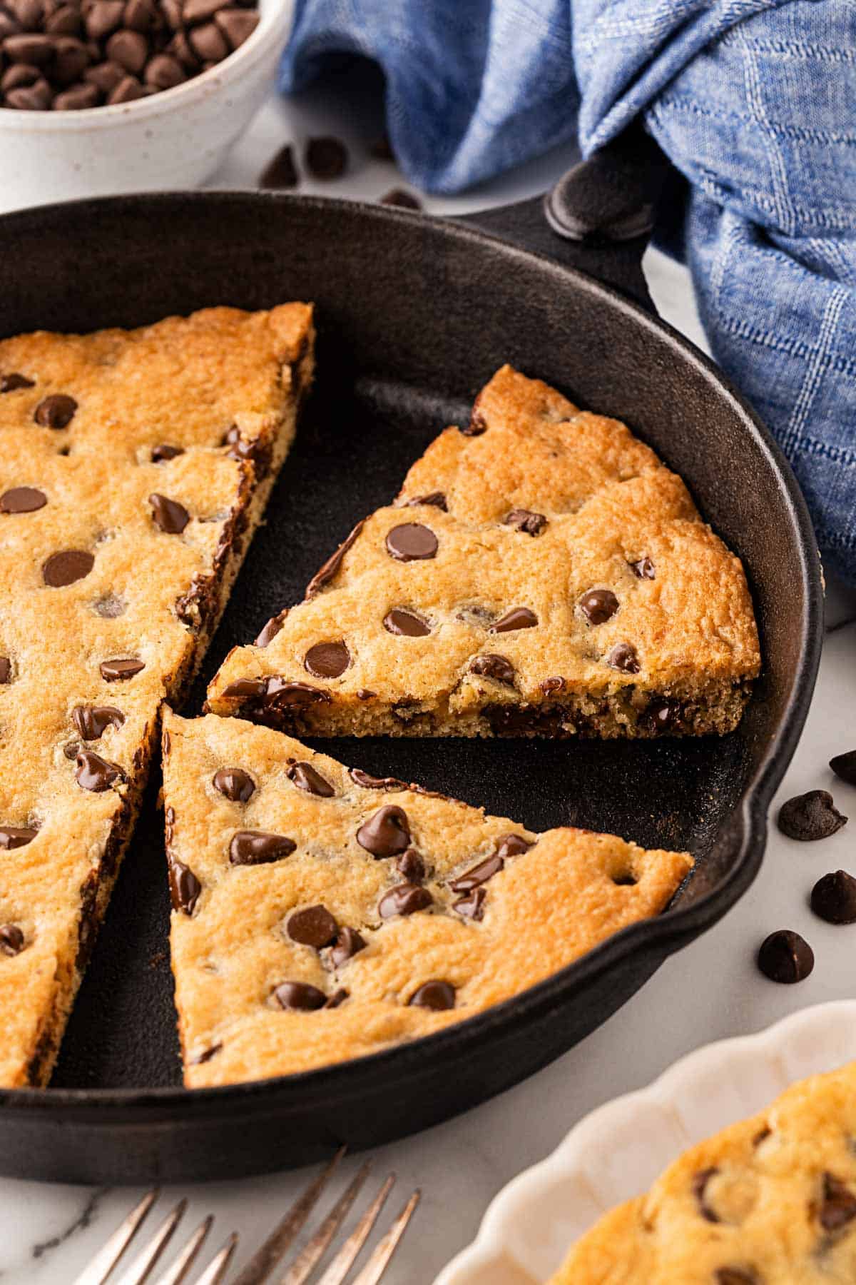 Closeup of sliced chocolate chip skillet cookie inside the pan, showing gooey melted chocolate chips
