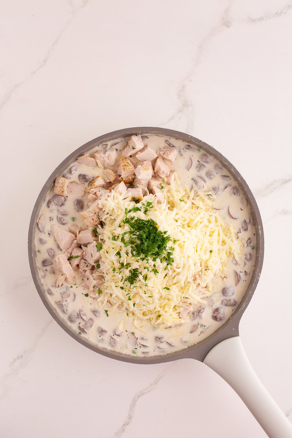 Cooked turkey chunks, shredded cheese, and chopped parsley added into the creamy mushroom sauce