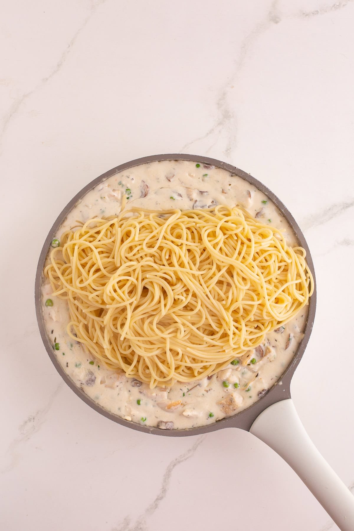 Cooked spaghetti added to the skillet