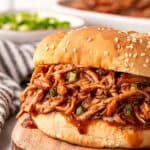 Barbeque shredded slow cooker chicken piled high on a sesame bun, ready to serve
