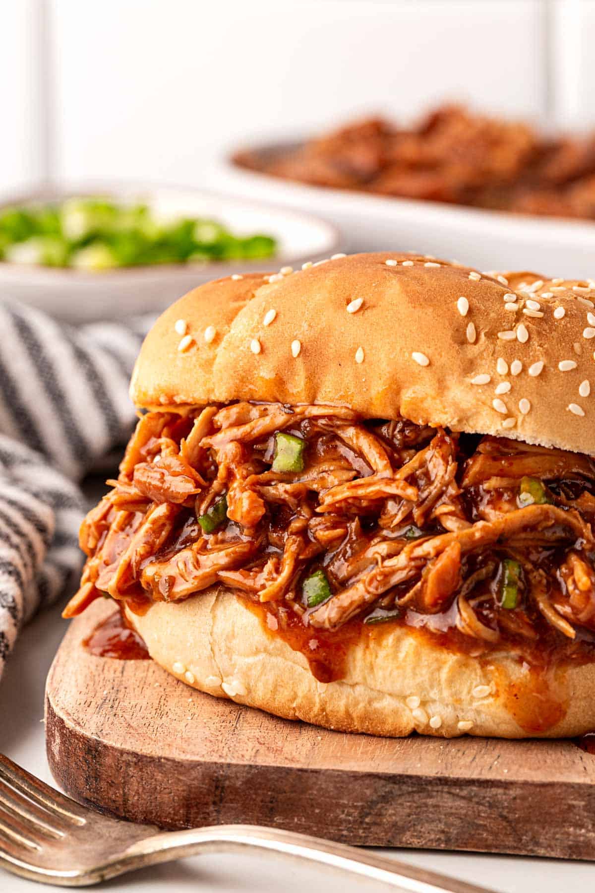 Barbeque shredded slow cooker chicken piled high on a sesame bun, ready to serve