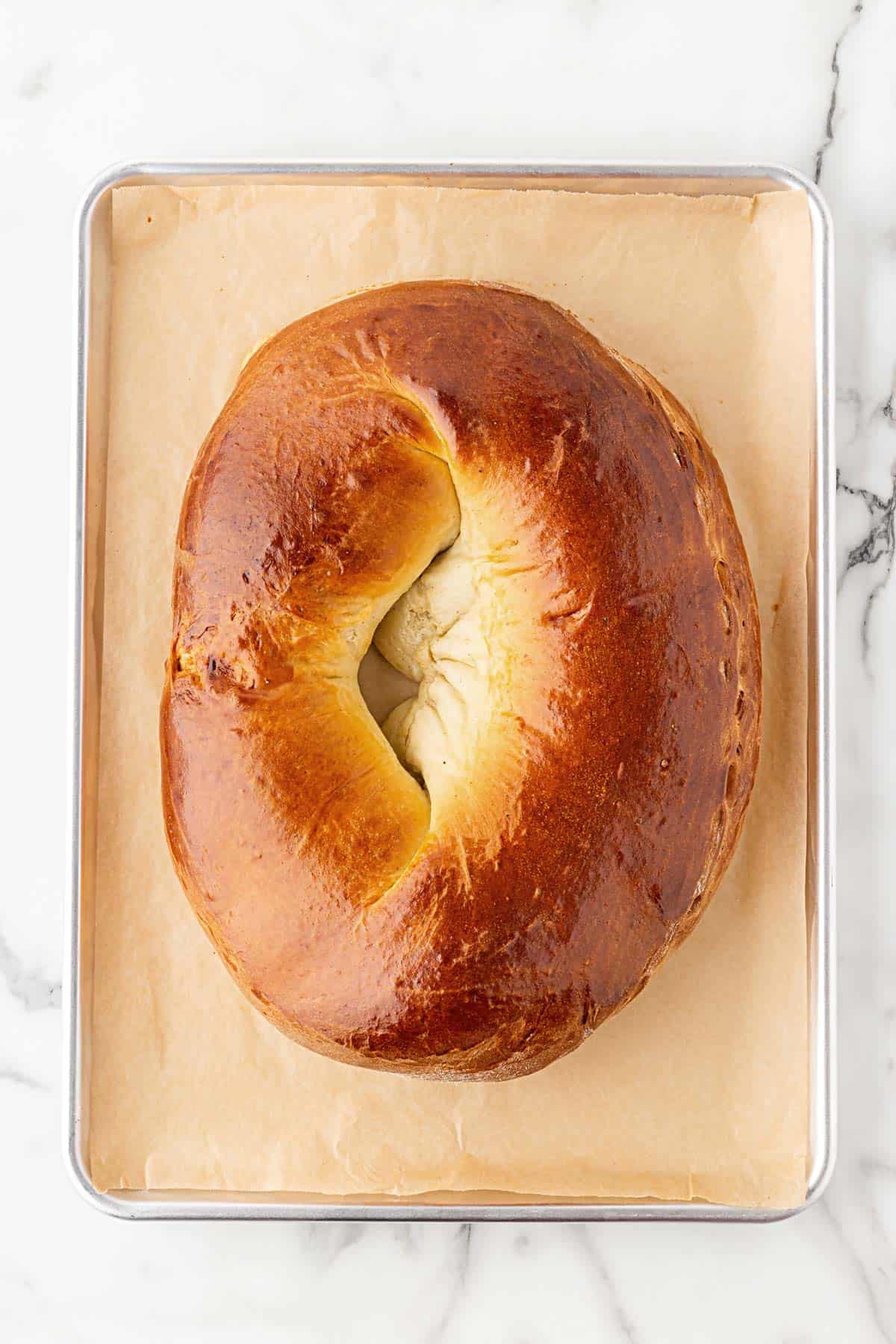 Baked king cake ring on a parchment-lined sheet pan before icing