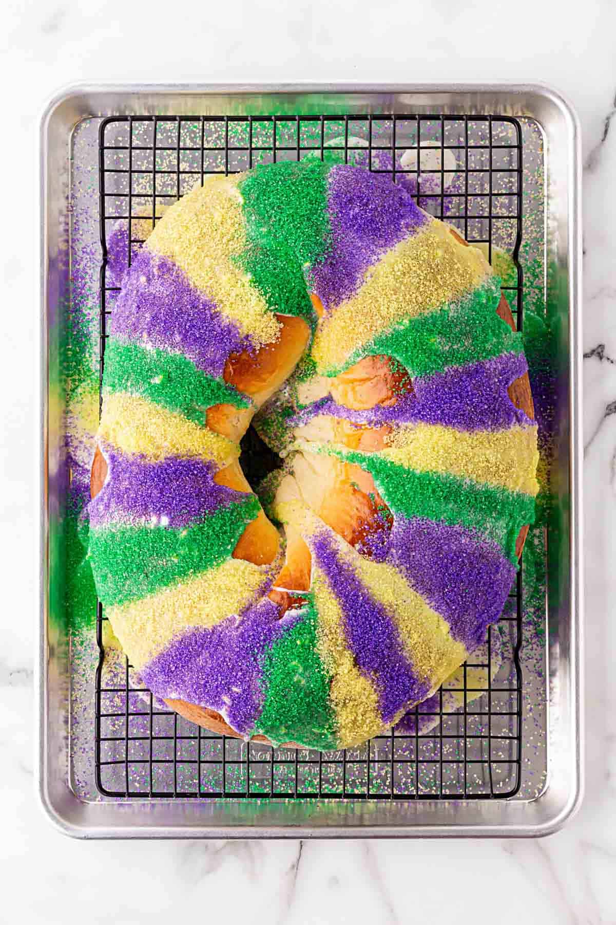 Overhead shot of a fully decorated king cake with purple, green, and gold sugar stripes