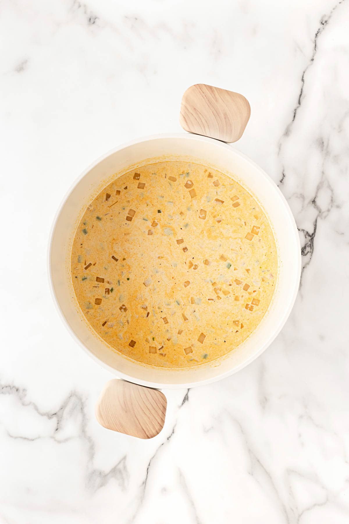 Creamy soup base simmering with diced vegetables in the pot