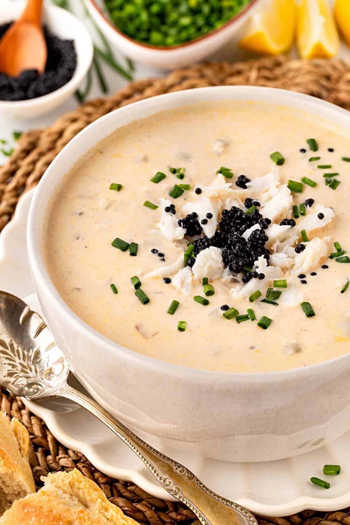 Bowl of she crab soup garnished with chives, crab meat, and black caviar