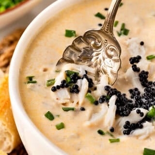 Closeup of a spoon lifting crab meat and caviar from creamy she crab soup