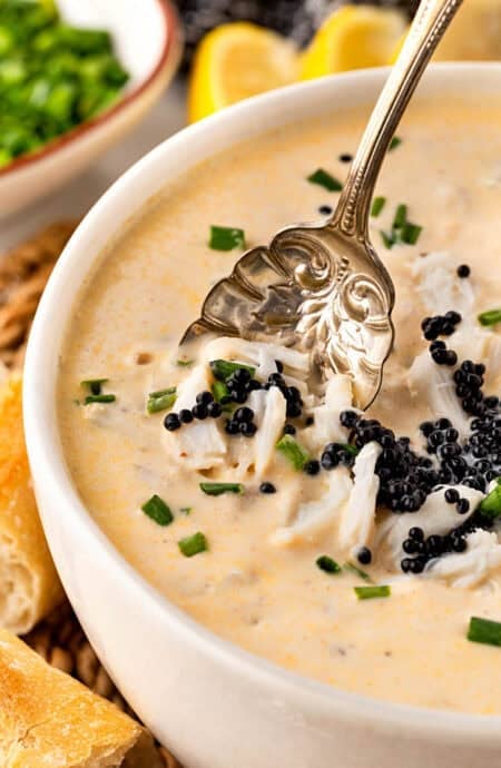 Closeup of a spoon lifting crab meat and caviar from creamy she crab soup