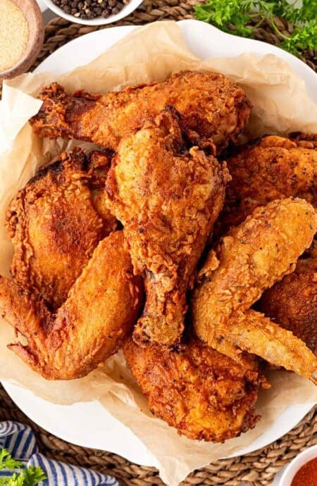 Overhead shot of crispy spicy fried chicken piled on a plate with crunchy coating