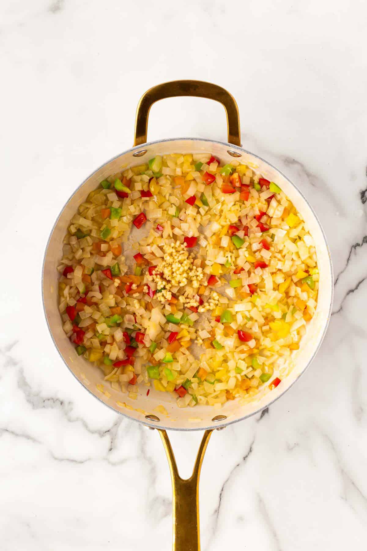 Diced onions, peppers, and garlic sautéing in a skillet
