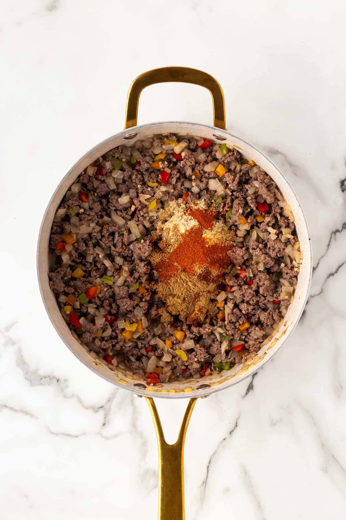 Ground beef mixture in a skillet topped with seasoning spices