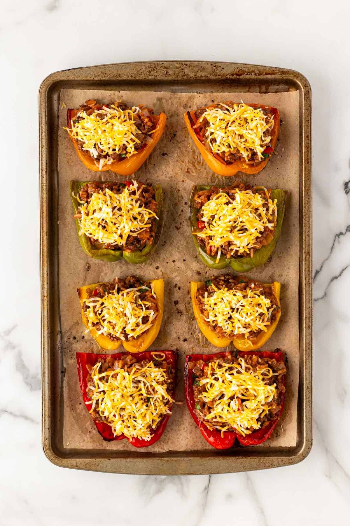 Bell pepper halves filled with meat mixture and topped with shredded cheese before baking