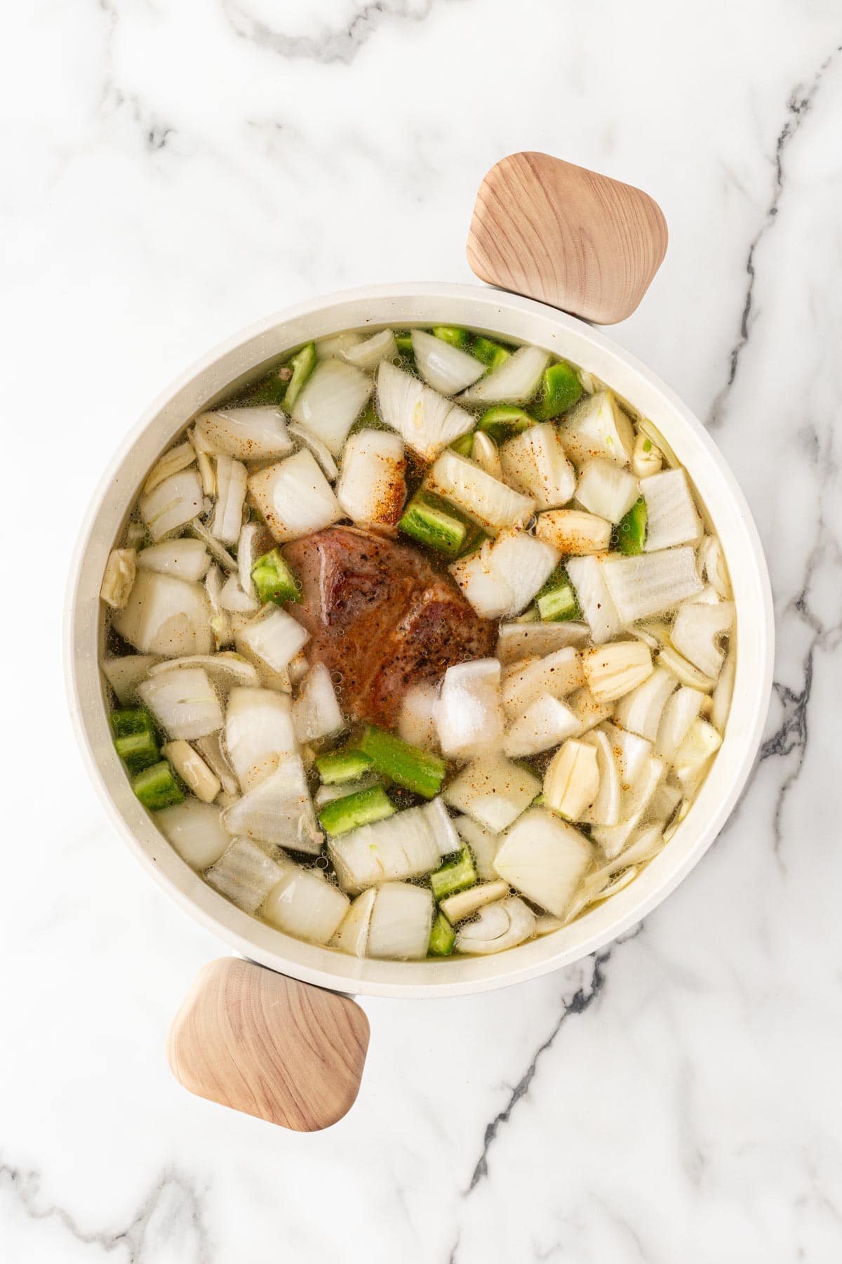 Cooked pork shoulder and vegetables simmering together in a pot
