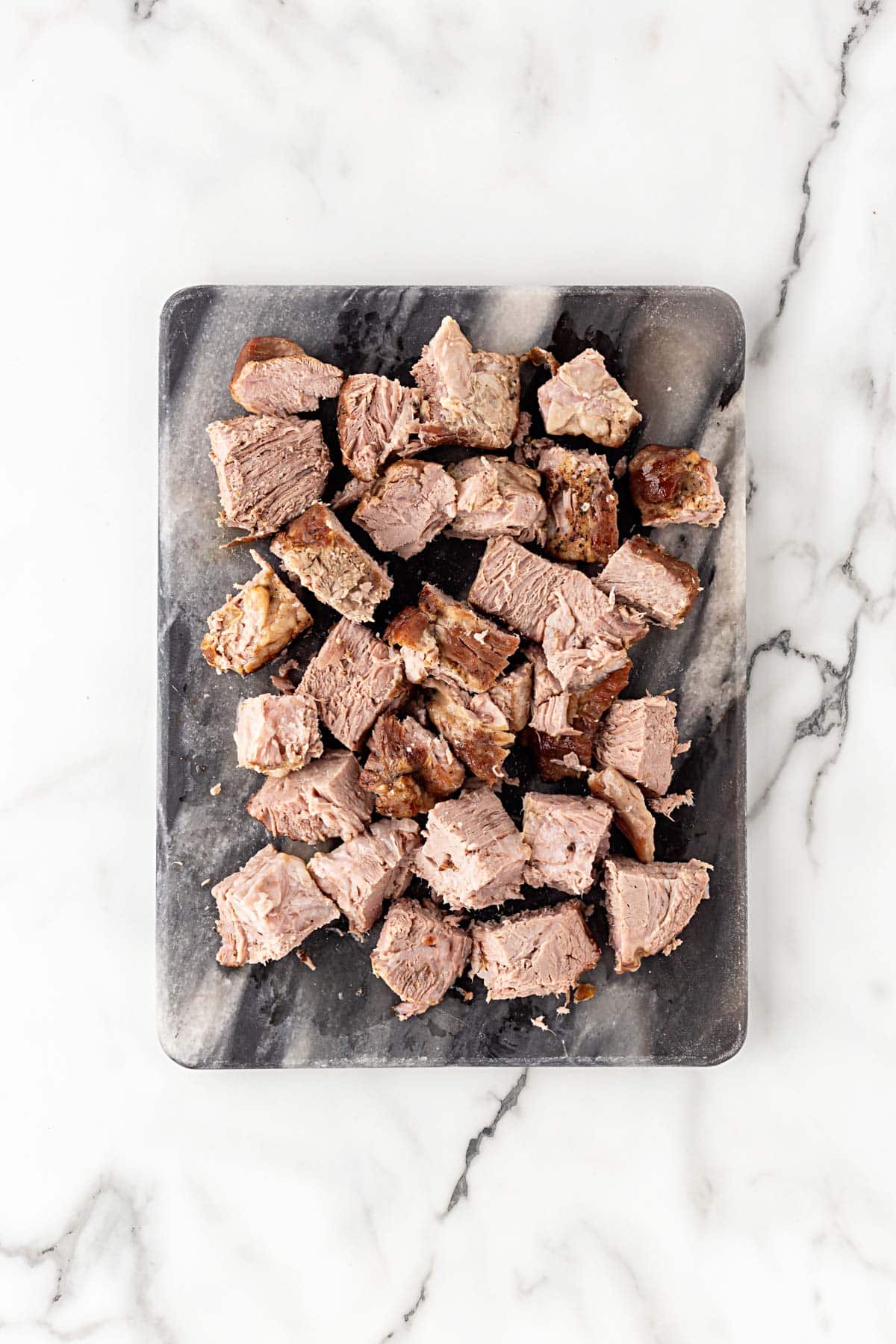 Chopped cooked pork shoulder pieces arranged on a cutting board