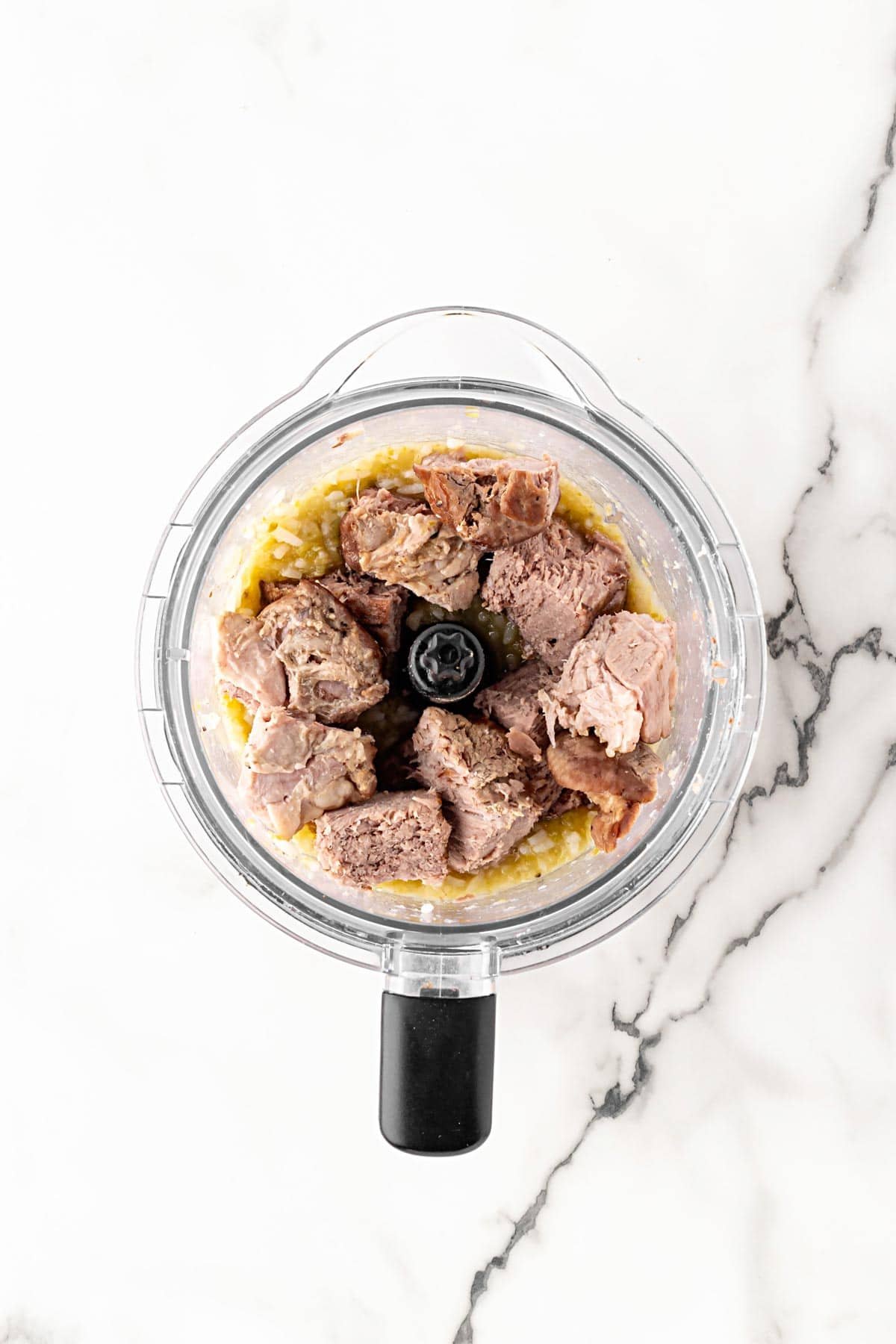 Cooked pork added to a food processor with softened vegetables