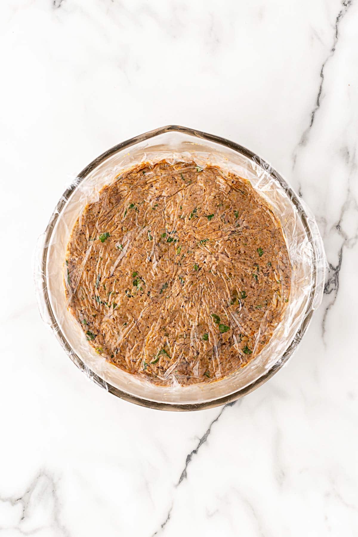 Boudin mixture smoothed and wrapped tightly with plastic wrap in a bowl