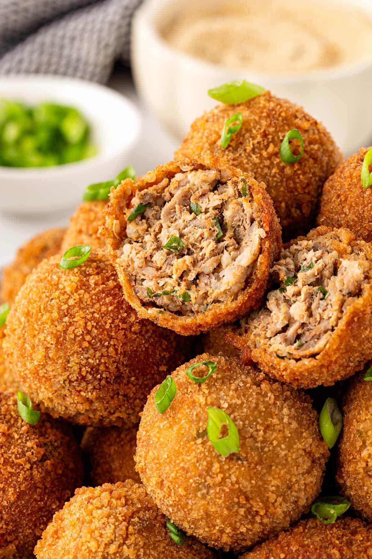 Boudin balls with one cut open, showing the seasoned sausage and rice filling inside