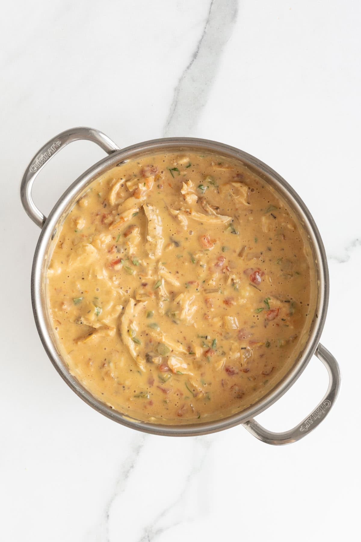 Thick, creamy chicken sauce mixed with vegetables in a pot