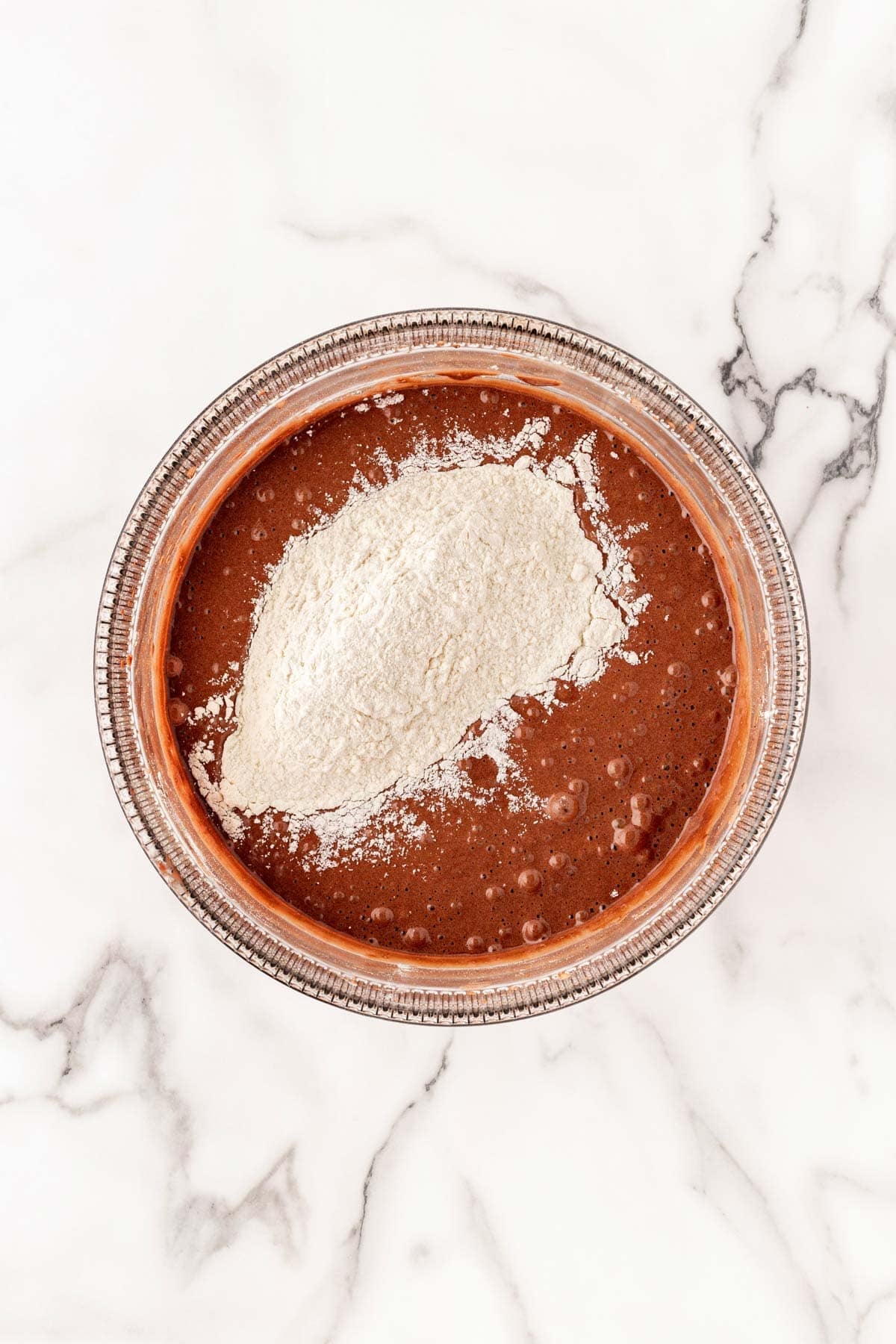 Flour added on top of chocolate batter in a glass bowl