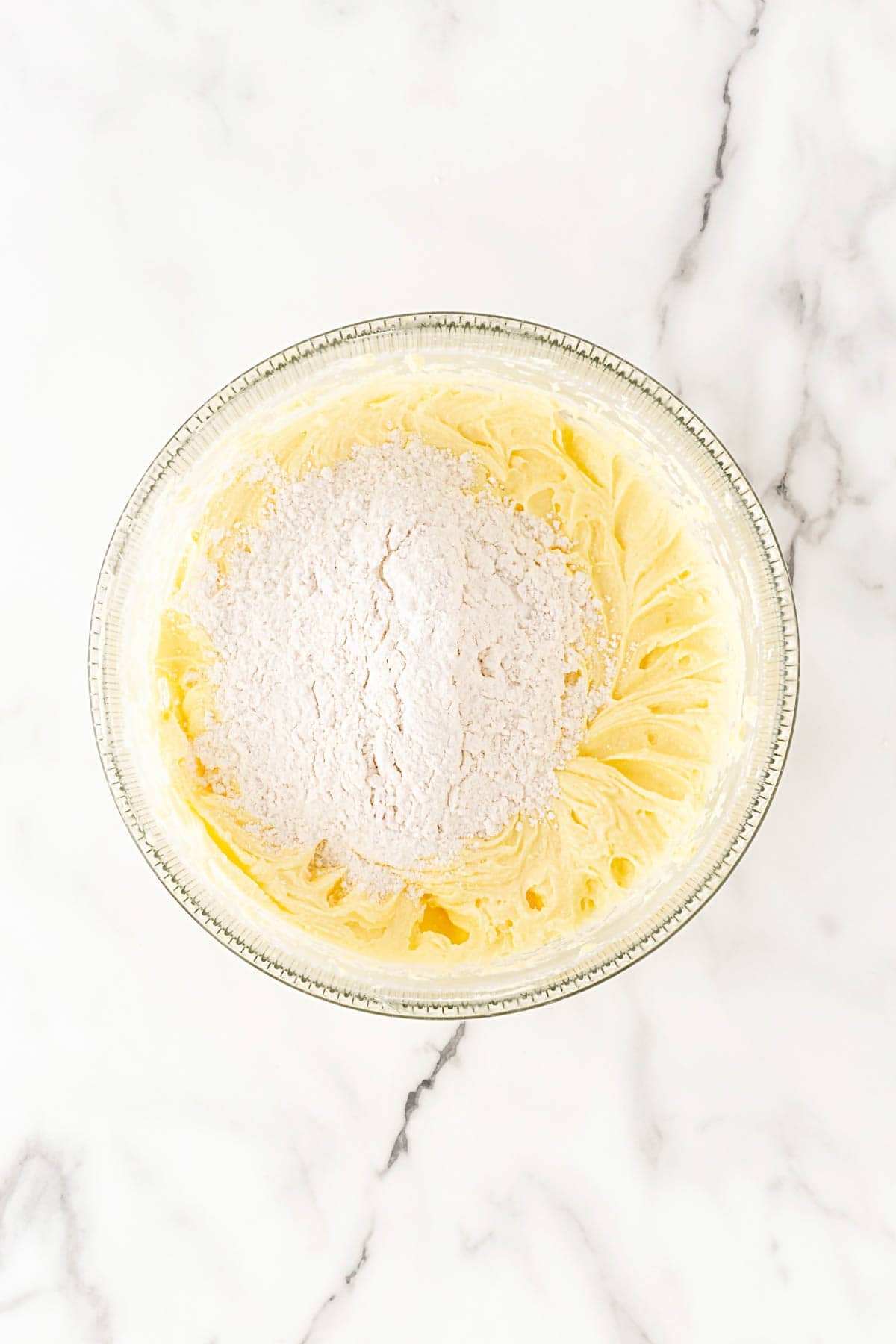 Flour added to a bowl of creamed butter and sugar mixture