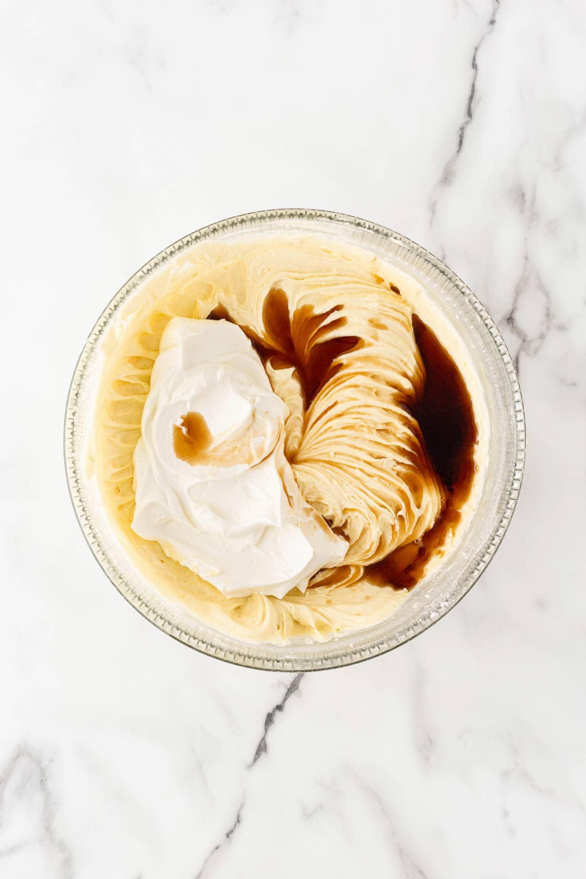 Sour cream and vanilla extract added to the creamed butter mixture in a glass bowl