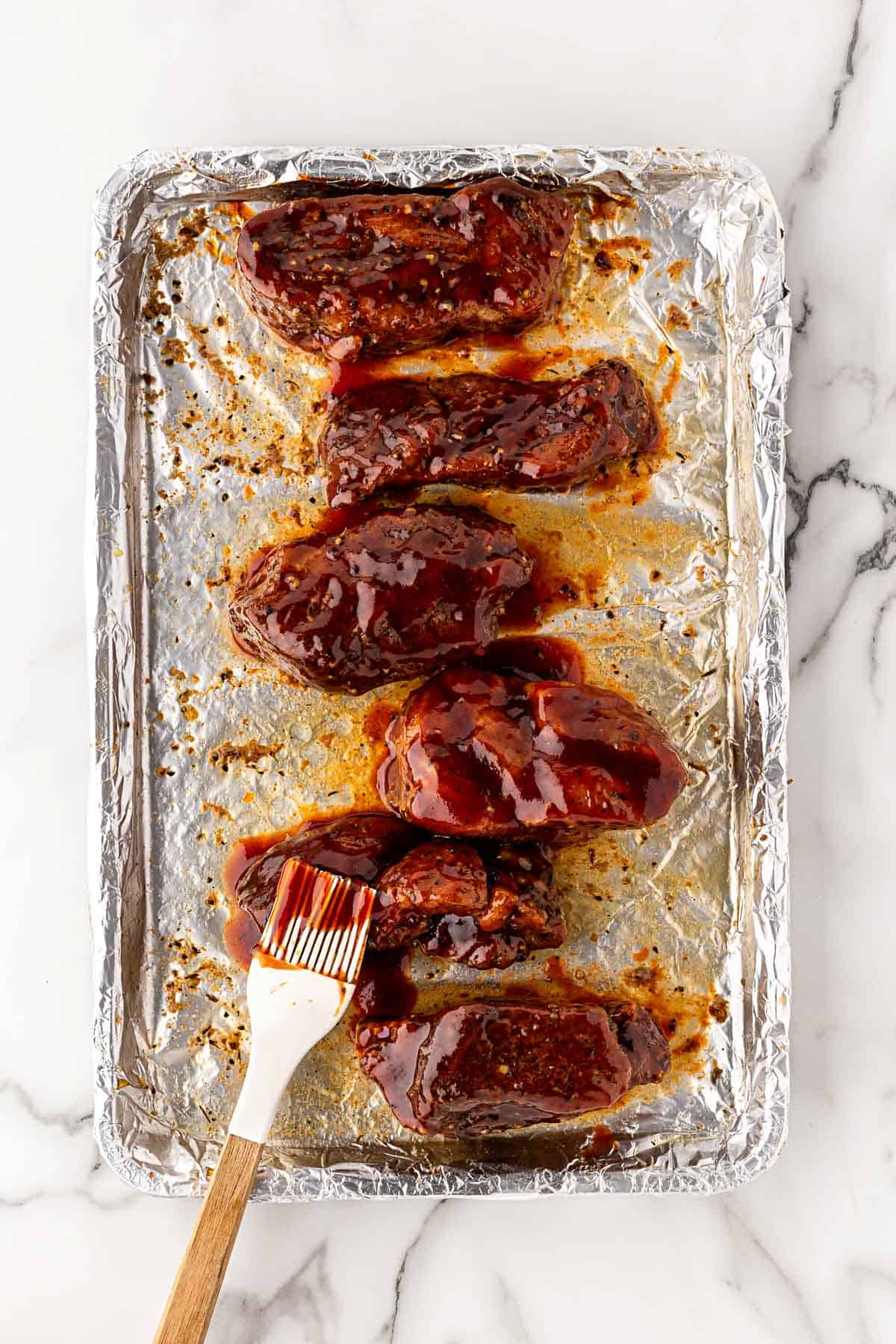 Pork ribs brushed with barbecue sauce using a pastry brush