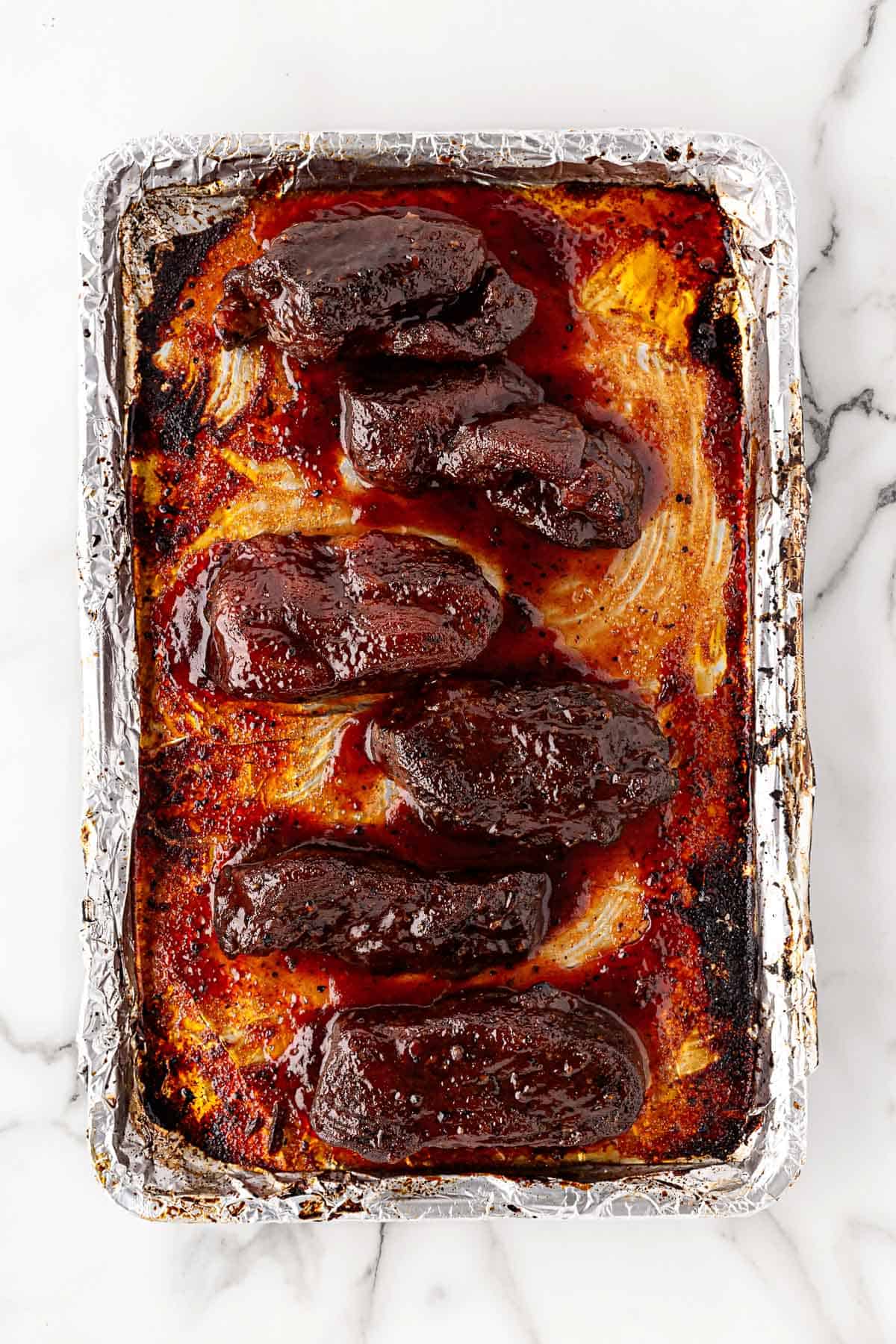 Glazed country style pork ribs caramelized in sauce on a foil-lined baking sheet