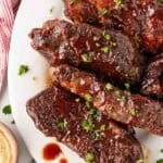 Overhead shot of glazed country style pork ribs with parsley garnish sitting on a white plate
