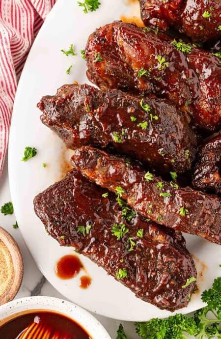 Overhead shot of glazed country style pork ribs with parsley garnish sitting on a white plate