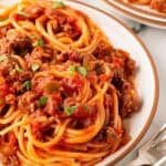 Closeup of spaghetti with meat sauce topped with chopped parsley on a plate
