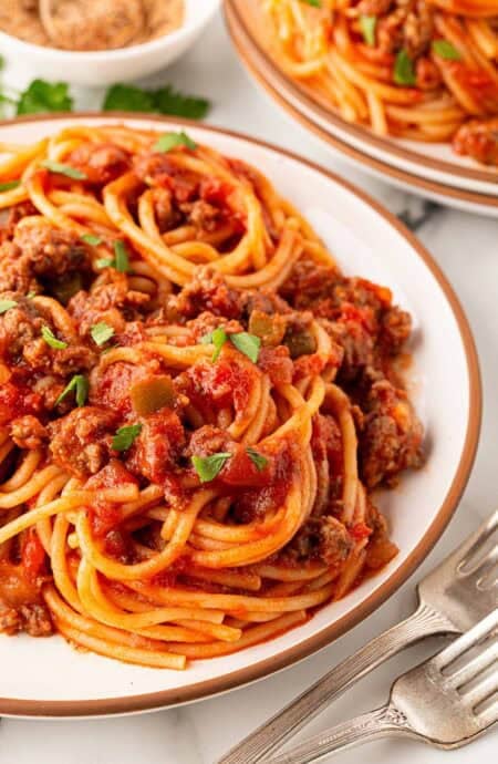 Closeup of spaghetti with meat sauce topped with chopped parsley on a plate
