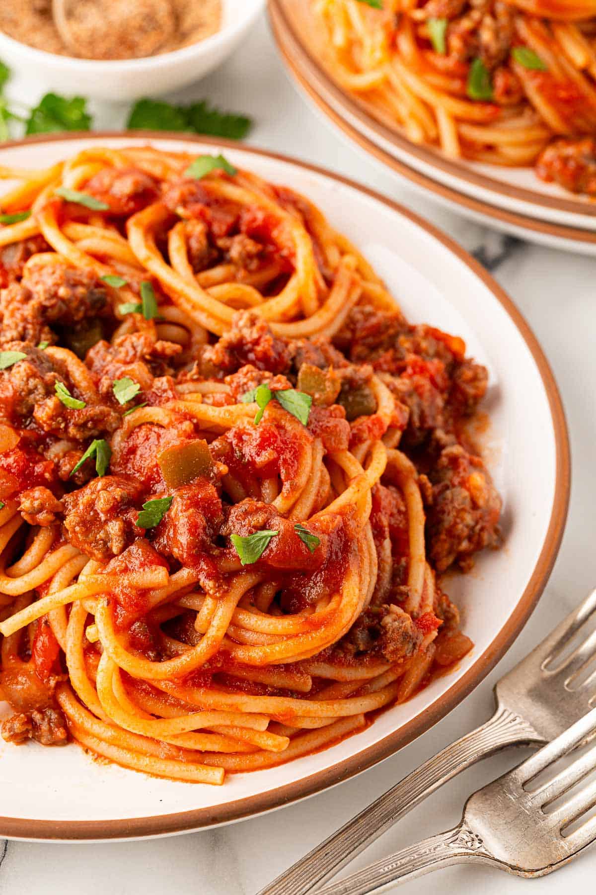 Closeup of spaghetti with meat sauce topped with chopped parsley on a plate