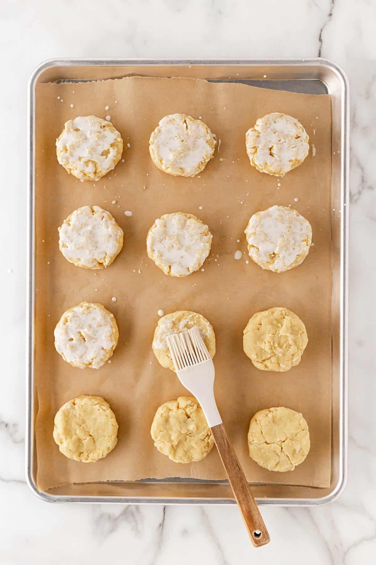 Shortcakes brushed with cream on a baking sheet before baking