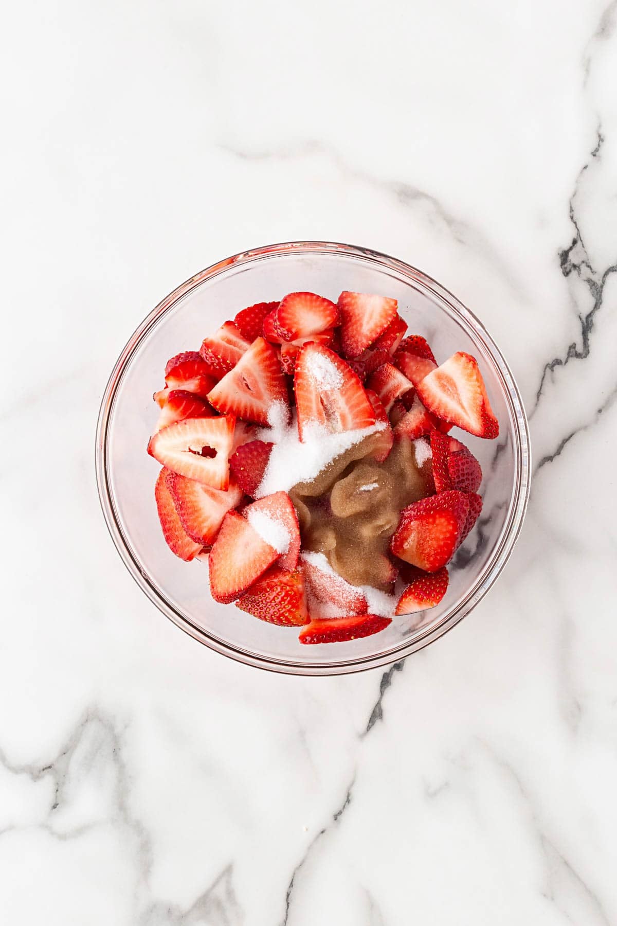 Sliced strawberries mixed with sugar and vanilla extract in a glass bowl