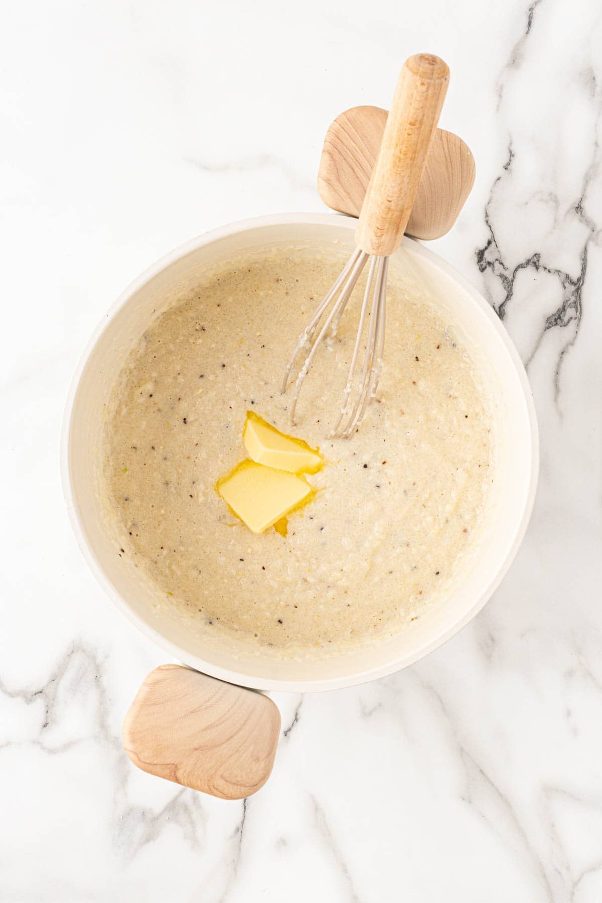 Creamy grit mixture with butter melting on top and whisk