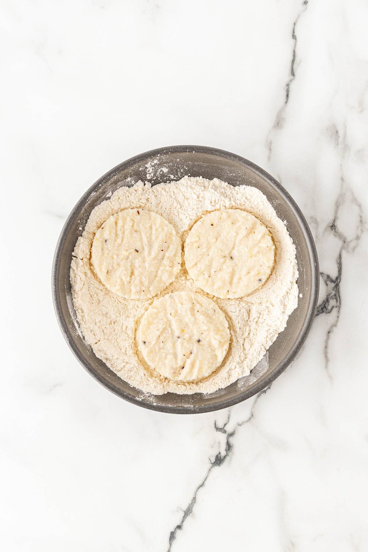 Grit rounds dredged in seasoned flour in a shallow bowl
