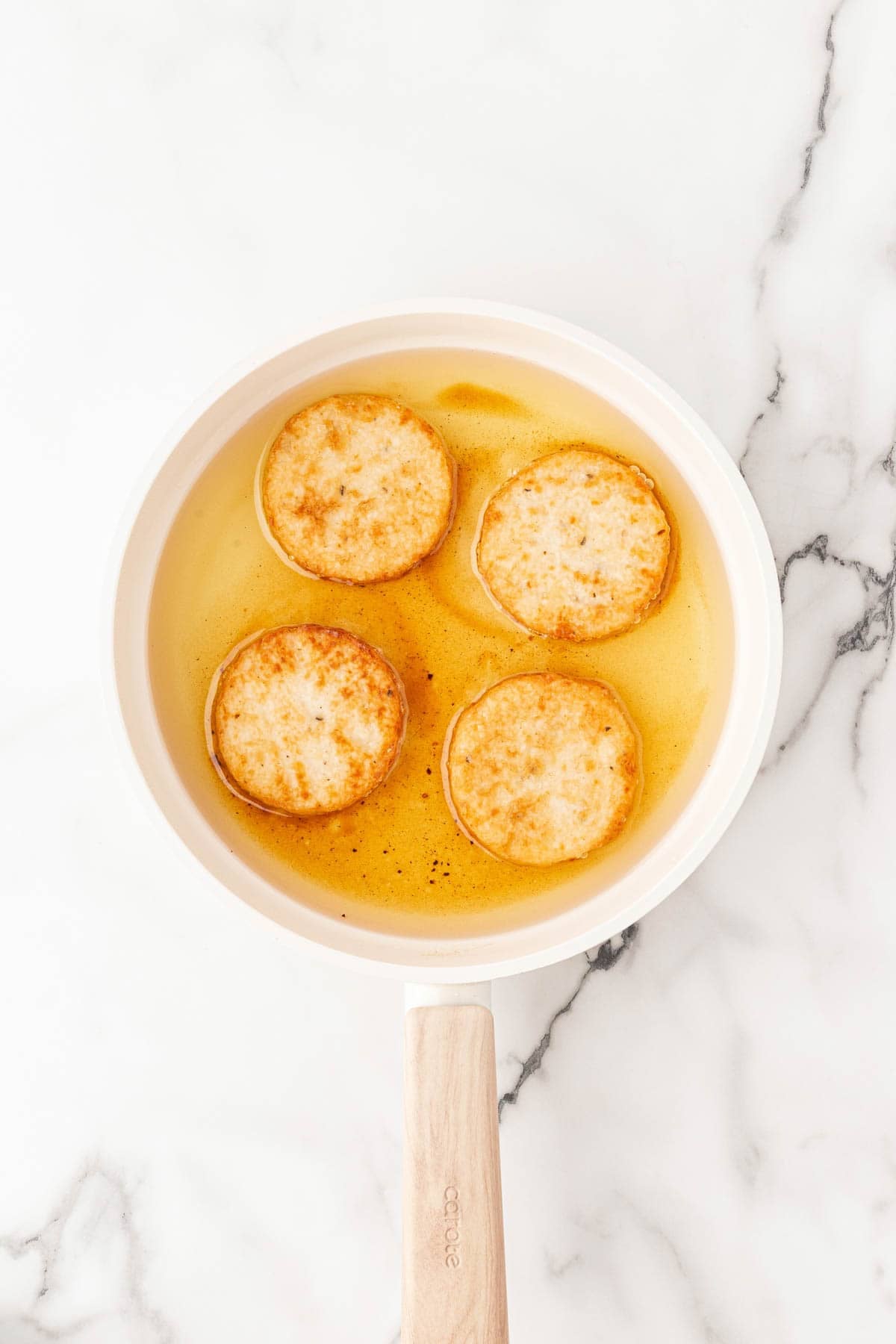 Grit cakes frying in oil in a skillet until golden